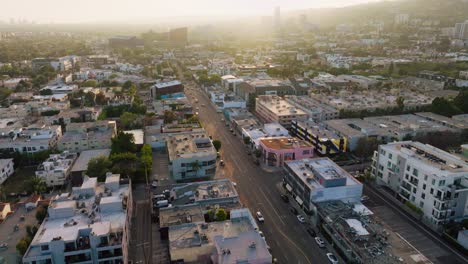 Flug-über-Die-Melrose-Avenue-Im-Sonnigen-Los-Angeles,-Drohnenaufnahme-über-Einer-Belebten-West-Hollywood-Street-Mit-Autos