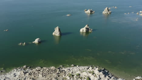 Aerial-view-of-tufa-formations-at-Mono-Lake,-showcasing-their-intricate-and-rugged-structures-amid-the-serene-desert-landscape-under-a-sunny-sky