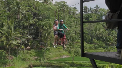 Una-Pareja-Disfruta-De-Un-Emocionante-Paseo-En-Una-Bicicleta-Tándem-Suspendida-Sobre-Las-Exuberantes-Terrazas-De-Arroz-De-Tegallalang,-Bali,-Indonesia.