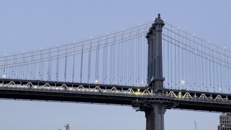 Close-up-view-of-the-Manhattan-Bridge-illuminated-at-twilight,-showcasing-the-intricate-details-of-its-structure-and-the-soft-evening-light-against-a-clear-sky