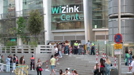 People-stand-outside-the-WiZink-Center,-Madrid's-indoor-sports,-trade,-and-music-event-arena,-as-they-prepare-for-a-concert-in-Madrid,-Spain