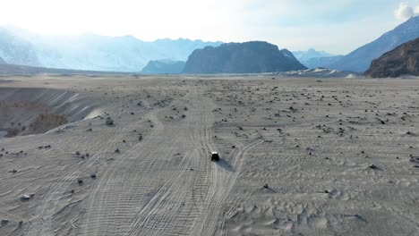 Rear-shot-of-vehicle-driving-on-Sarfaranga-Cold-Desert-with-beautiful-landscape-of-mountains-in-Skardu-Valley,-Pakistan