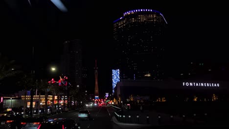 Driving-on-Las-Vegas-Strip-at-Night,-Passing-by-Fontainebleau-Casino-Hotel,-Nevada-USA