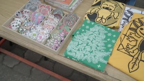 Table-with-a-variety-of-colorful-stickers-and-t-shirts-for-sale-from-entrepreneurial-artists