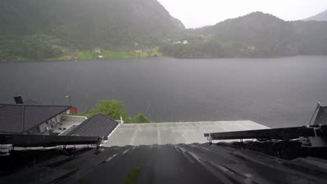 Rooftop-view-of-sea-in-Norway-during-heavy-rain,-flanked-by-solar-panels-mounted-on-metal-roof