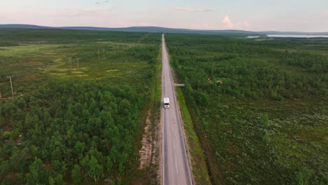 AERIAL:-flying-backwards-in-front-of-a-RV-on-a-arctic-forest-road-in-Lapland