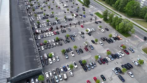 A-crowded-parking-lot-beside-a-large-building,-aerial-view