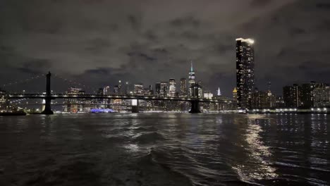 Una-Vista-Fascinante-Del-Horizonte-De-Manhattan-Y-Los-Puentes-Reflejados-En-El-East-River-Por-La-Noche,-Con-Espectaculares-Nubes-En-Lo-Alto,-Capturando-El-Paisaje-Nocturno-Y-La-Belleza-Urbana-De-La-Ciudad.