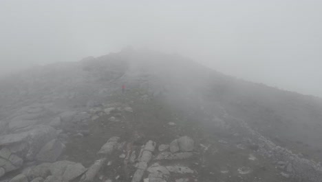 Luftaufnahmen-Einer-Drohne,-Die-Einen-Einsamen-Wanderer-Auf-Seinem-Weg-Durch-Dichten-Nebel-In-Der-Sierra-De-Guadarrama-Verfolgen