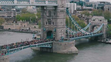 Angled-Slow-Circling-Shot-of-Marathon-Runners-on-Tower-Bridge-with-North-London