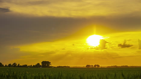 Timelapse-golden-sky-colour-moving-clouds-and-sun,-green-grass-open-field