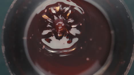 Red-wine-dropping-into-wine-glass-and-rippling-close-up-wide-macro-slow-motion