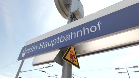 Schild-Des-Berliner-Hauptbahnhofs,-Schwenk-LKW-Aufnahme-Von-Links-Nach-Rechts-Und-Zurück-Und-Lensflare-Der-Sonnenstrahlenreflexion-4k