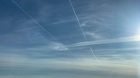 Aerial-view-of-some-jet-contrails-in-a-bright-and-sunny-sky-shot-from-another-airplane-flying-bellow