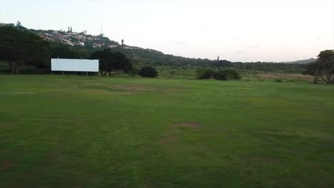 Drone-flying-low-over-cricket-training-nets-and-an-abandoned-old-building-change-rooms-with-a-white-score-board-over-a-rugby-field-Harlequins-on-the-Bluff-in-Durban