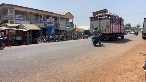 traffic-car-truck-and-cars-driving-fast-on-a-road-in-Wulugu-village,-Northern-Ghana