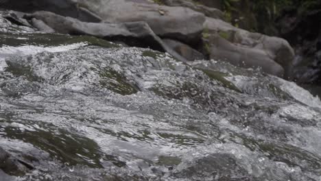 Slow-motion-shot-of-a-crystal-clear-Goa-Rang-Reng-stream-cascading-over-rocks-in-Bali,-Indonesia