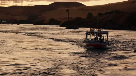 Drone-Siguiendo-Un-Barco-Navegando-Por-El-Río-Nilo-En-Egipto-Al-Atardecer