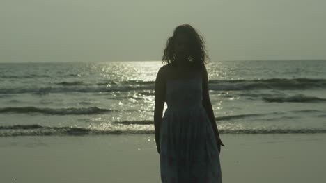 Woman-walking-close-to-the-camera-at-the-beach-during-sunset