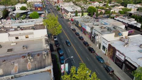 Drone-Approaching-Shops-and-Pedestrians-on-Melrose-Avenue,-Cars-Parked-Along-Busy-LA-Street-in-Daytime