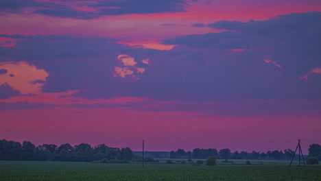 Vibrant-pink-twilight-over-farmland-fields---cloudscape-time-lapse-at-dusk