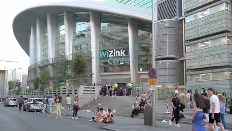 Concertgoers-stand-outside-the-WiZink-Center,-Madrid's-indoor-sports,-trade,-and-music-event-arena,-as-they-prepare-for-a-concert-in-Madrid,-Spain