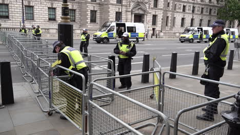 Police-officers-form-a-loose-cordon-on-a-metal-security-barrier-marking-the-edge-of-a-sterile-area-and-prevent-members-of-the-public-from-entering-during-a-major-public-order-event