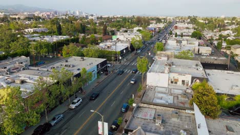 Flying-Over-Melrose-in-Daytime,-Busy-Los-Angeles-Street-with-Cars-Driving-Through,-as-Seen-by-Drone