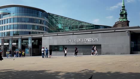 Visitors-at-the-Tower-of-London-ticket-office-on-a-sunny-day,-some-standing-and-some-walking