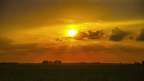 Golden,-glowing-sky-over-the-silhouette-of-farmland-fields---glorious-sunset-time-lapse