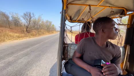 rickshaw-Tuk-Tuk-driving-around-deserted-road-in-Wulugu-village,-Northern-Ghana