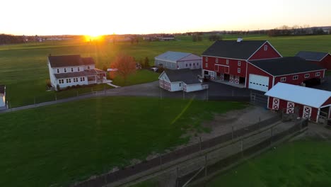 Golden-hour-sunset-over-American-farm-with-red-barns-and-quaint-home