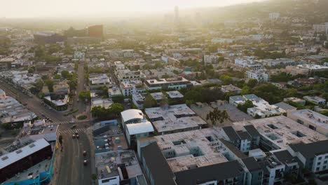 Aerial-Drone-Footage-of-West-Hollywood-Intersection-in-Daytime,-Hazy-Sunlight-Hitting-Rooftops-on-Melrose