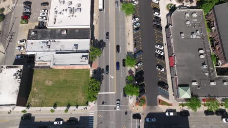 Downtown-Dearborn,-Michigan-intersection-with-traffic-and-drone-video-tilting-up-to-city