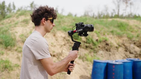 Male-with-sunglasses-adjust-gimbal-stabilizer-with-camera-equipment,-Czechia