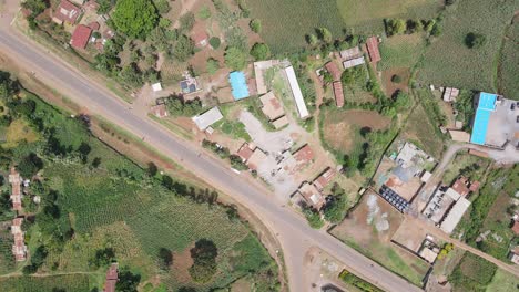 African-village-by-busy-highway-in-Southern-Kenya,-aerial-top-down