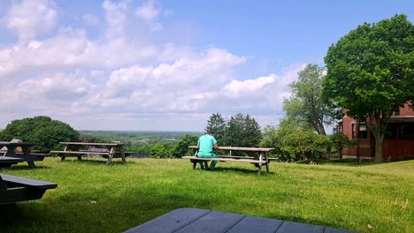 Unidentifiable-man-eating-lunch-on-picnic-bench-at-Western-Promenade-Portland,-Maine