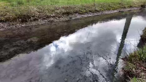 El-Agua-Fluye-Suavemente-A-Través-Del-Canal,-Reflejando-El-Cielo-Arriba,-Reflejando-El-Concepto-De-Armonía-Entre-La-Tierra-Y-El-Cielo.