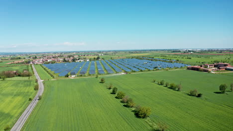 Vista-Aérea-De-Una-Granja-Solar-En-Un-Campo-Verde-Bajo-Un-Cielo-Azul-Claro