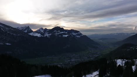 Clip-De-Drone-Que-Muestra-Un-Valle-Con-Montañas-Cubiertas-De-Nieve-Al-Amanecer-Temprano-En-La-Mañana