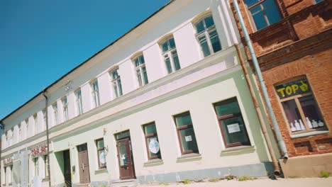 Footage-of-a-girl-passing-by-a-red-brickstone-and-white-concrete-building-in-a-Daugavpils-street,-capturing-the-architectural-charm-of-the-Baltic-region