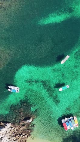 Crystal-clear-waters-with-corals-and-boats-viewed-from-a-drone-in-vertical-mode