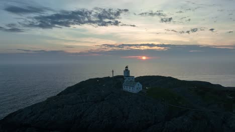 Aproximación-Aérea-Al-Faro-De-Marsteinen-Al-Atardecer,-Dando-Vueltas-Para-Revelar-Detalles-Y-Edificios-De-La-Isla,-Con-Oscuridad-En-El-Lado-Opuesto