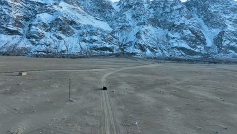 Toma-De-ángulo-Alto-De-Un-Vehículo-Conduciendo-Por-El-Frío-Desierto-De-Sarfaranga-En-El-Valle-De-Skardu-En-Pakistán