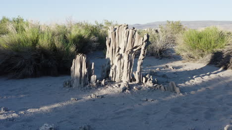 Close-up-aerial-view-of-unique-tufa-formations-at-Mono-Lake,-highlighting-the-intricate-columns-amidst-the-desert-vegetation-under-a-clear-blue-sky