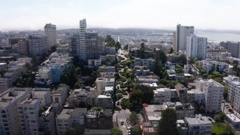 Aerial-wide-reverse-pullback-shot-of-cars-going-down-Lombard-Street,-the-most-crooked-street-in-the-world,-on-top-of-Russian-Hill-in-San-Francisco,-California