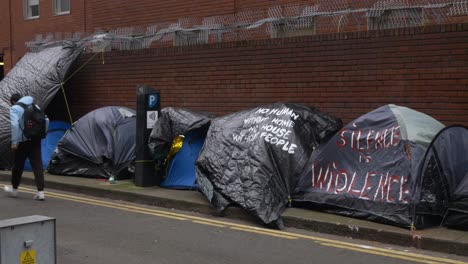 Eine-Person-Geht-An-Zelten-Vorbei,-Die-Von-Obdachlosen-Mit-Protestschildern-In-Dublin-Aufgestellt-Wurden