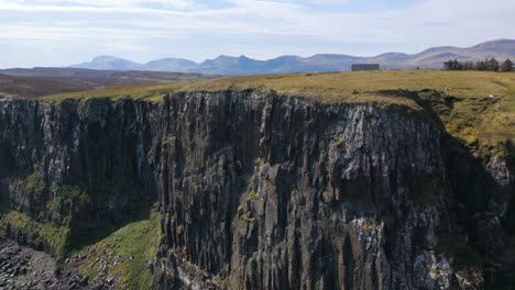 Aerial-flying-near-cliff-on-coast-of-Skye-on-sunny-day,-Scotland