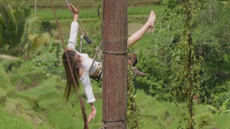 Una-Mujer-Alegre-Se-Balancea-Por-Encima-De-Las-Exuberantes-Terrazas-De-Arroz-De-Tegallalang,-Bali,-Indonesia.