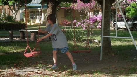 Young,-black-haired,-lonely-girl-plays-on-swing-set-alone-and-pushes-empty-swing--static-medium-shot